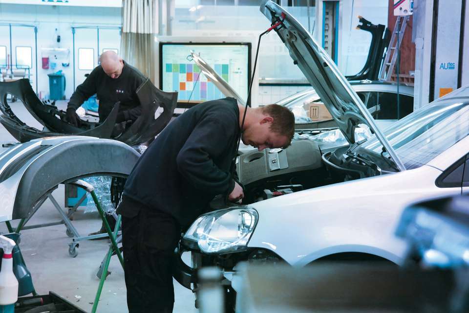 Technicians working on vehicles with the Carbeat production board on the workshop floor