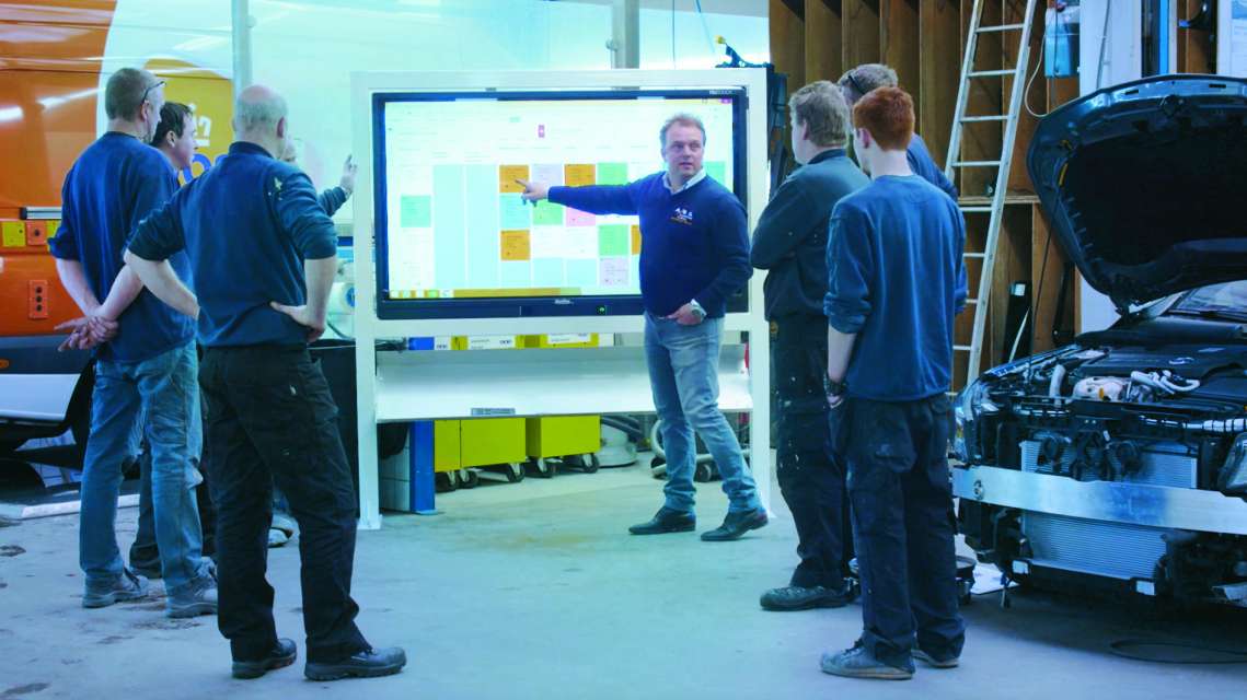 A bodyshop team reviewing their workflow together on a Carbeat touchscreen